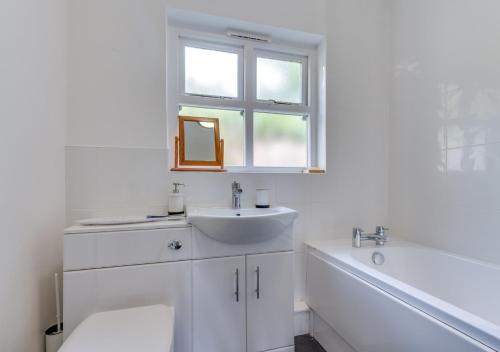 ein weißes Bad mit einem Waschbecken und einem Fenster in der Unterkunft St. Brides Cottage in Saundersfoot