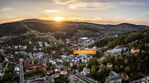 a view of a city with the sunset in the background at Centrum Cicha, Sun & Snow in Krynica Zdrój