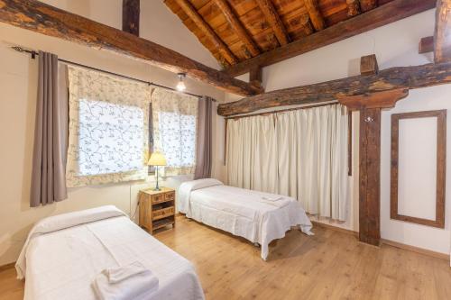 two beds in a room with wooden ceilings at La Casona y Casitas de Tabladillo in Santa María la Real de Nieva