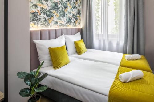 a white bed with yellow pillows and a window at Garden House Apartments in Krakow