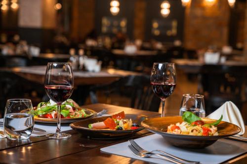 a table with two plates of food and wine glasses at Maxi Park Hotel & Spa in Velingrad