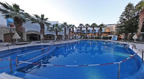 a large blue swimming pool with palm trees and buildings at Parkim Ayaz Hotel in Gümbet