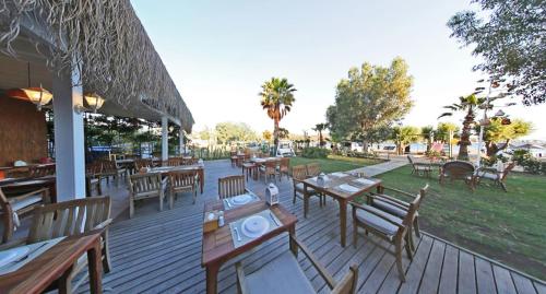 a wooden deck with tables and chairs on it at Parkim Ayaz Hotel in Gümbet