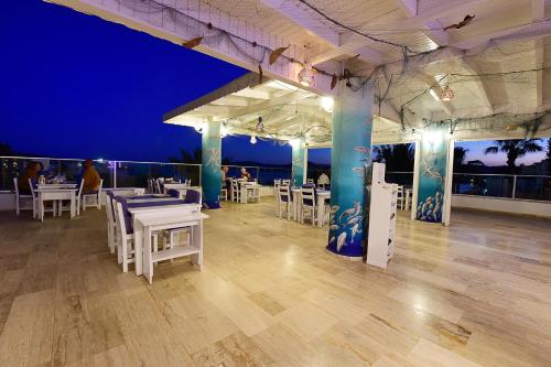 a restaurant with white tables and chairs and the ocean at Parkim Ayaz Hotel in Gümbet