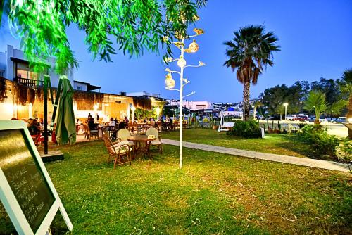 a park with a table and chairs and a palm tree at Parkim Ayaz Hotel in Gümbet