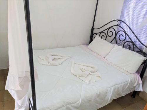 Una cama con sábanas blancas y almohadas blancas. en STC.SAFARI LODGE, en Oldeani