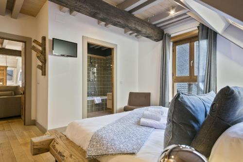 a bedroom with a bed and a couch and a tv at LUDERNA - Dúplex Pin Nere in Salardú