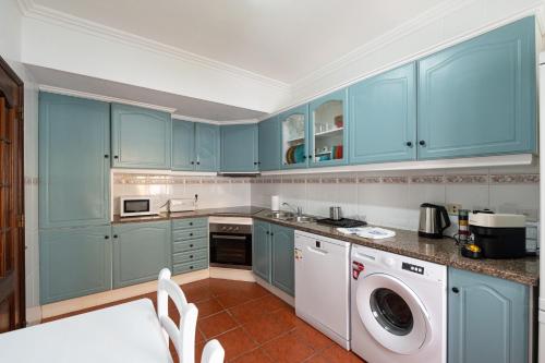 a kitchen with blue cabinets and a washer and dryer at Lovely house, Paredes Alenquer in Alenquer