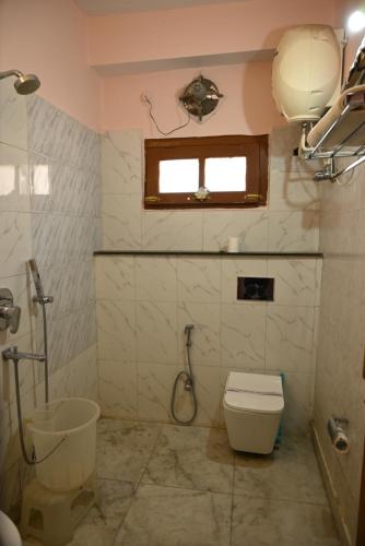 a bathroom with a shower and a toilet and a window at Hotel Atul Regency in Rāmpur
