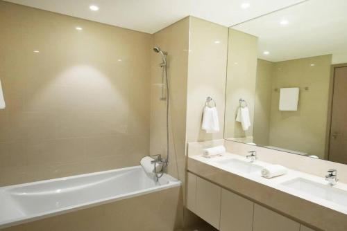 uma casa de banho com 2 lavatórios, uma banheira e um espelho. em Brown Stone Holiday Homes Act em Dubai