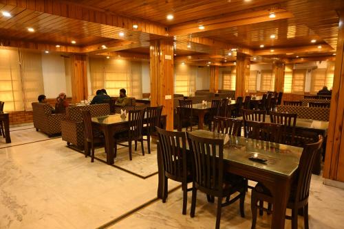 a restaurant with tables and chairs and people sitting at tables at Hotel Atul Regency in Rāmpur