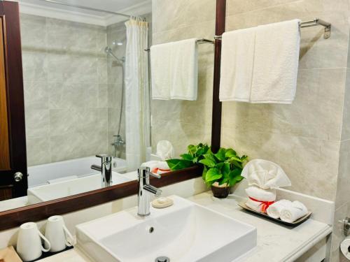 a bathroom with a sink and a mirror and a tub at Muong Thanh Grand Phuong Dong in Vinh
