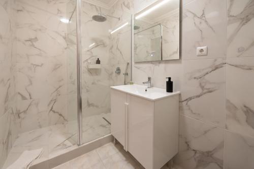 a white bathroom with a sink and a shower at Lovely house, Paredes Alenquer in Alenquer
