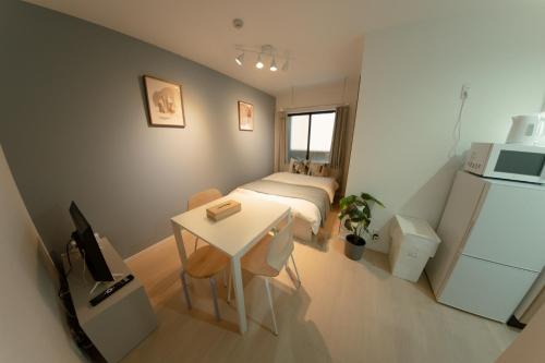 a small room with a bed and a table and a refrigerator at Ashe Maison Tennoji West II in Osaka