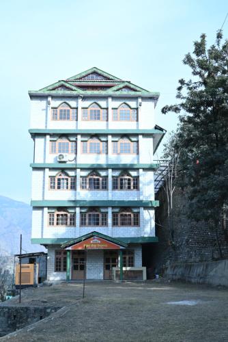 a tall white building with windows on a hill at Hotel Atul Regency in Rāmpur