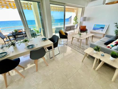 un salon avec une table et des chaises et l'océan dans l'établissement La Plage, Résidence La Fontaine, à La Seyne-sur-Mer