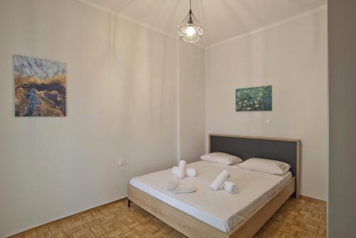1 dormitorio con 1 cama con sábanas blancas y 2 pinturas en Like Home, en Atenas