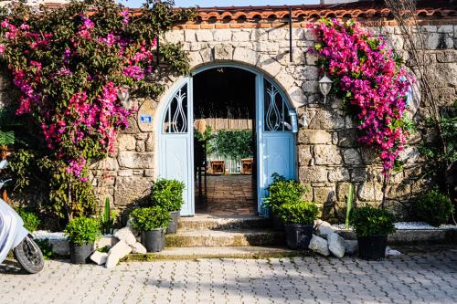 un edificio de piedra con una puerta azul y flores rosas en Dort Mevsim Alacati, en Alacati