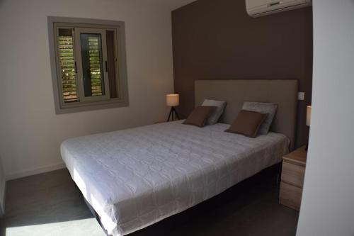 une chambre avec un grand lit blanc avec une fenêtre dans l'établissement Superbe rez-de-jardin de villa MACCHIA 2, Proche des plages de Santa giulia, à Porto-Vecchio