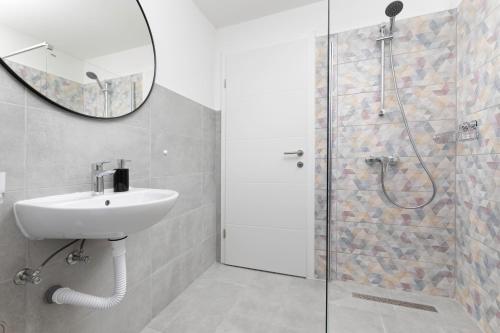 ein Badezimmer mit Waschbecken und Dusche mit Spiegel in der Unterkunft MIA Family Apartments Punat in Punat