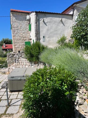 a bench in front of a building with some bushes at Villa Ana with jacuzzi & swimming pool in Cres