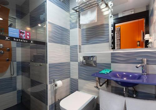 ein Badezimmer mit einem lila Waschbecken und einem WC in der Unterkunft JC Rooms Santo Domingo in Madrid