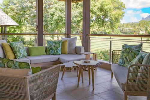 a screened in porch with a couch and a table at Anahita - Appartement Golf View - Hole 9 in Beau Champ