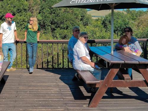 a group of people sitting around a picnic table with an umbrella at Midlands Forest Lodge in Balgowan