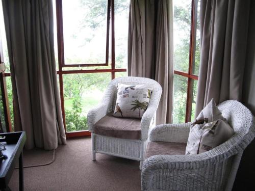 a living room with two chairs and a window at Midlands Forest Lodge in Balgowan