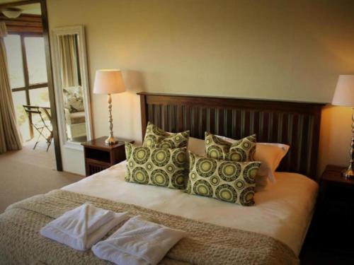 - une chambre avec un grand lit et des oreillers dans l'établissement Midlands Forest Lodge, à Balgowan