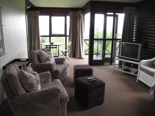 a living room with two chairs and a television at Midlands Forest Lodge in Balgowan