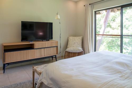 a bedroom with a bed and a tv and a window at Anahita - Appartement Golf View - Hole 9 in Beau Champ