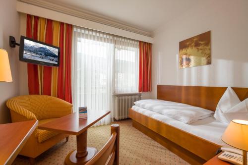 um quarto de hotel com uma cama, uma secretária e uma cadeira em Vital & Sporthotel Brixen em Brixen im Thale