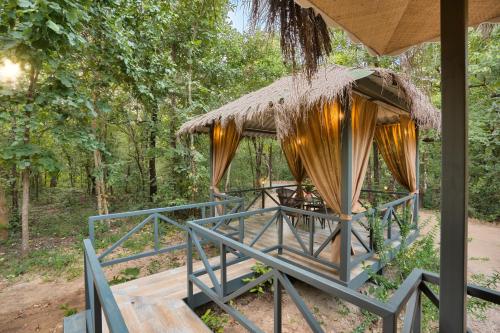 a gazebo with a table and a straw hut at Saj In The Forest, Pench in Seonī