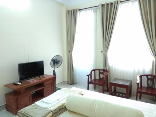 a living room with a bed and a tv and chairs at Nhà Khách 683 DN - by BAY LUXURY in Danang