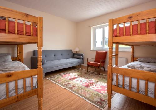 a bedroom with two bunk beds and a couch at 15 Lon Cernyw in Abersoch
