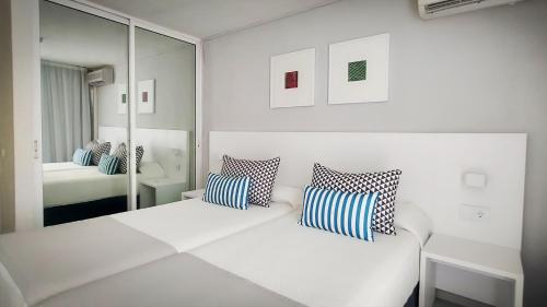 een witte kamer met een bed en een spiegel bij Hotel Blue Sea Lagos de Cesar in Puerto de Santiago