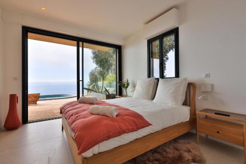 une chambre avec un grand lit avec vue sur l'océan dans l'établissement Villa Nest, à Rayol-Canadel-sur-Mer