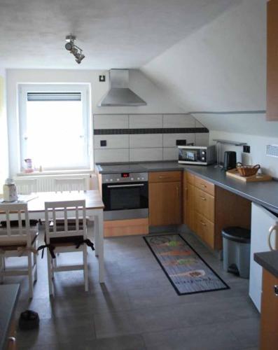 cocina con mesa, fogones y ventana en Ferienwohnung Hammerwaldblick im Dachgeschoss, en Selb