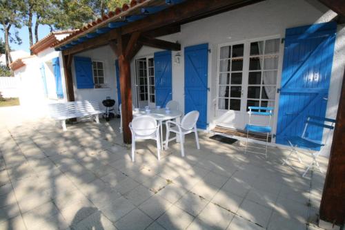 un patio avec une table et des chaises devant une maison dans l'établissement Maison dans les pins, à La Tranche-sur-Mer