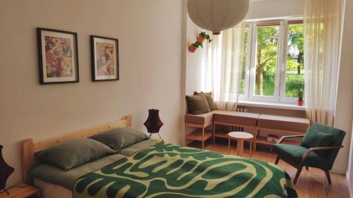 a bedroom with a bed and a couch and a window at Kwadrat i Kropka Apartament Zamość in Zamość