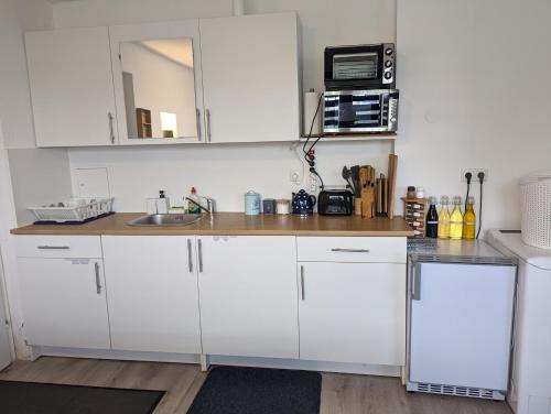 a kitchen with white cabinets and a sink and a microwave at Lovely studio with free parking on premisis in Asten