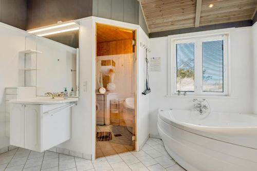 a white bathroom with a tub and a sink at Holiday Home Atmosphere On Harritsvej in Løkken