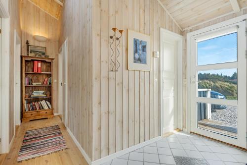 a hallway with a book shelf and a window at Holiday Home Atmosphere On Harritsvej in Løkken