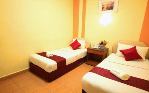 Una habitación de hotel con dos camas con almohadas rojas. en Sun Inns Hotel Batu Caves, en Cuevas de Batu
