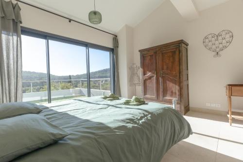 une chambre avec un grand lit et une grande fenêtre dans l'établissement La Bastide d'EAU - Exceptionnel, 5 Stars, 14 pers., à Saint-Cyr-sur-Mer