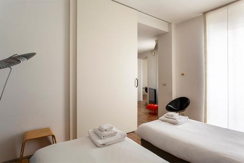1 dormitorio con 2 camas y silla negra en Milan City Chic - Porta Venezia, en Milán