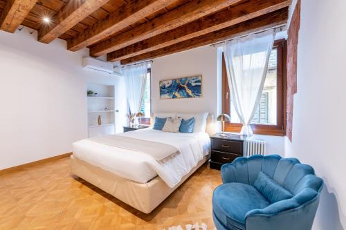 a bedroom with a bed and a blue chair at Sgarzerie Luxury Flat 2 rooms 120mq in Verona