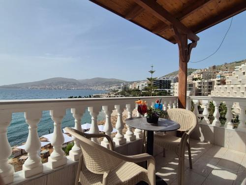 Un balcón con mesa y sillas y el mar. en ORCHIDS Hotel, en Sarandë