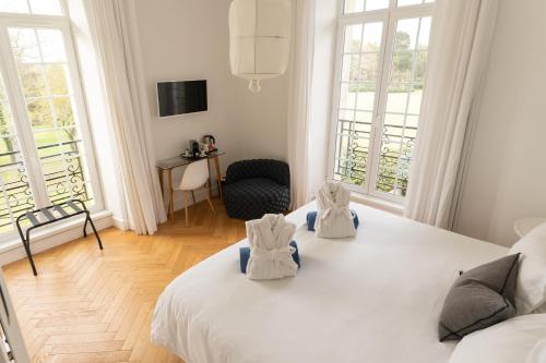 a bedroom with a large white bed with two bags on it at Les Garennes - Hôtel Spa Bénodet in Bénodet